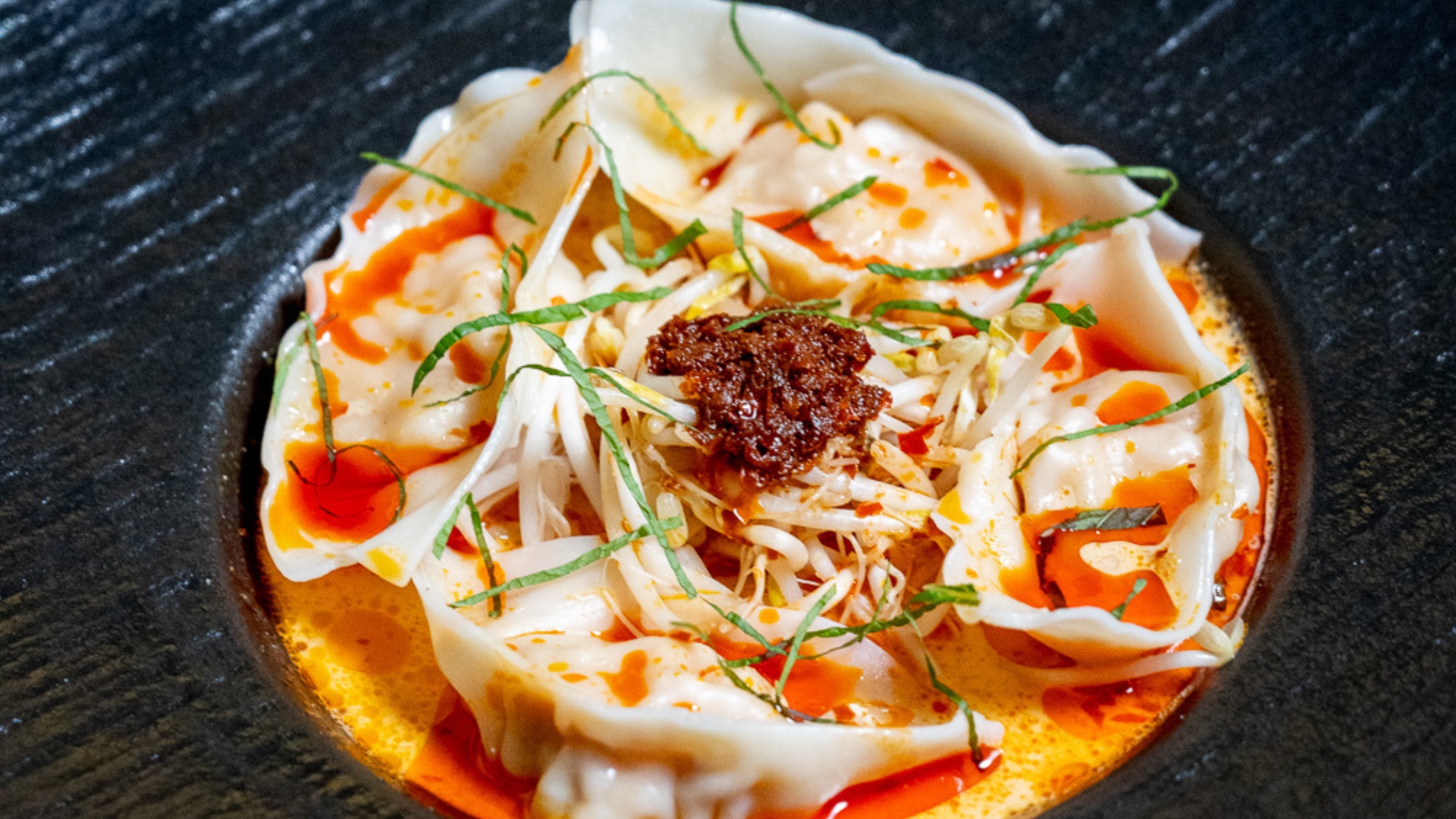 A close up picture of the laksa bombs at Ho Jiak Town Hall. Plump dumplings surrounded by a sea of coconut broth and sambal on top.