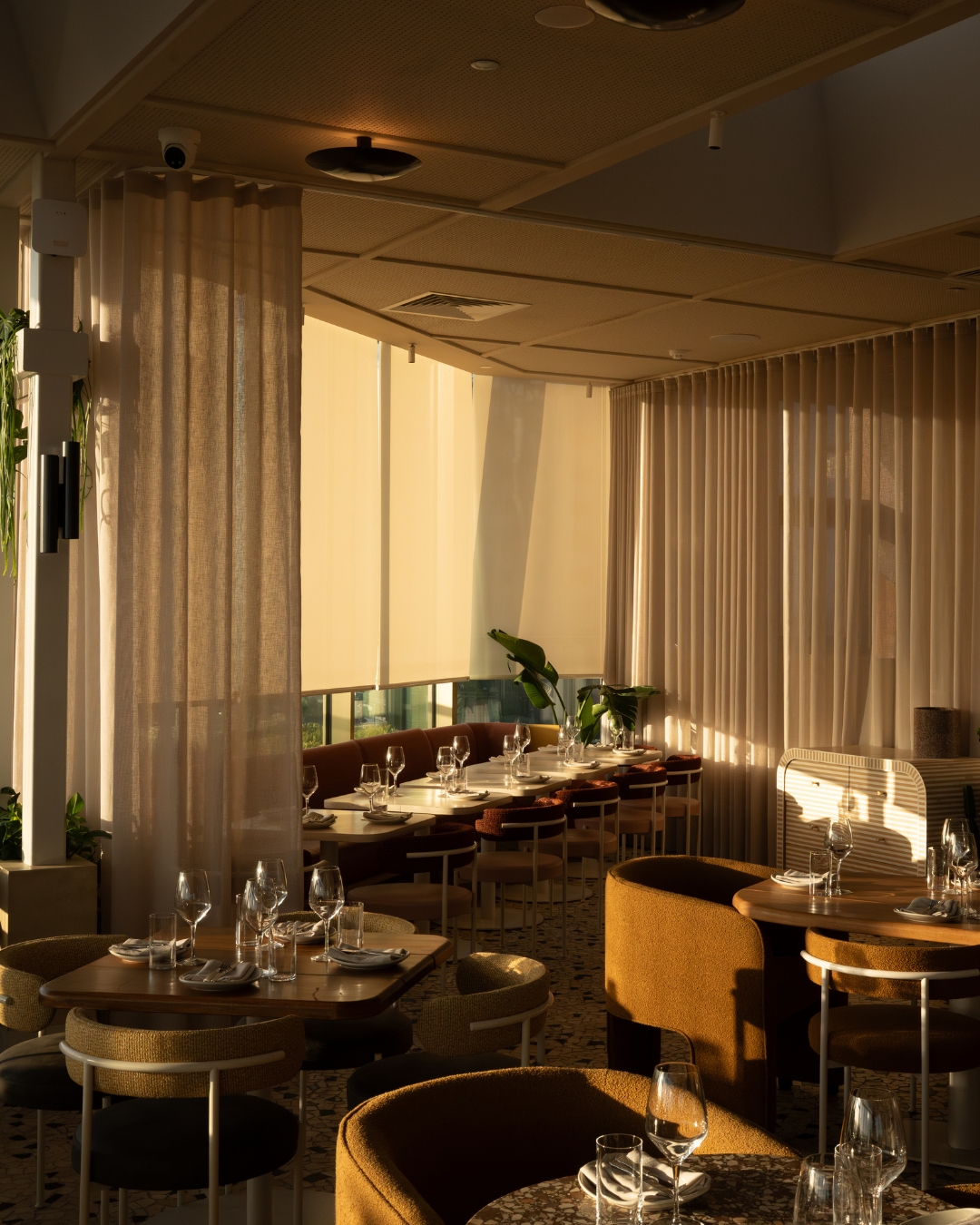 The Beverly dining room in dappled light features many neutral tones and terrazzo floors 