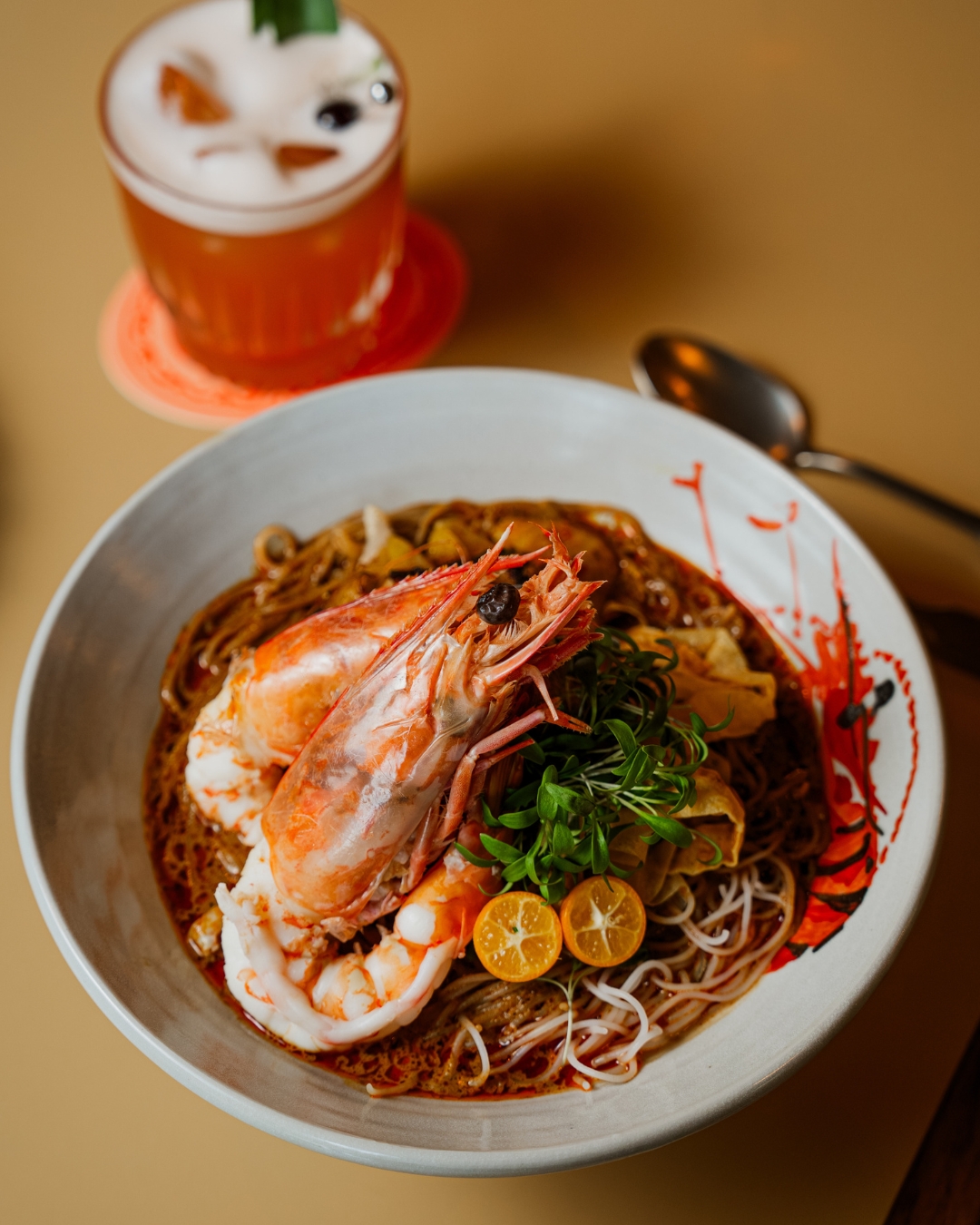 The Sarawak laksa featuring silky rice vermicelli noodles in a fragrant coconut broth infused with lemongrass, galangal, turmeric and chilli, that's then topped with poached chicken, king prawns and crisp bean sprouts.  