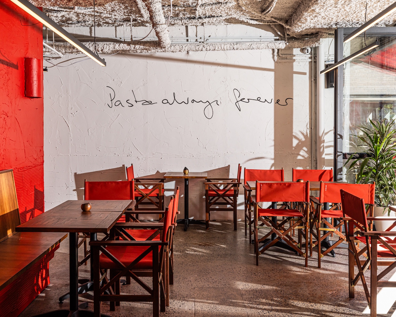 The dining room at new Sydney restaurant Pasta Shop, in Potts Point. A wall mural reads "Pasta always forever".