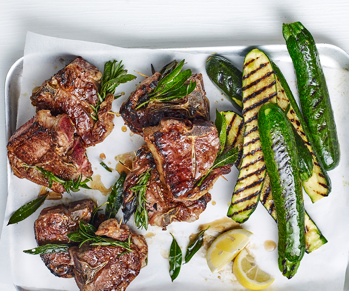 An aerial view of grilled lamb chops and grilled zucchini with lemon and rosemary.