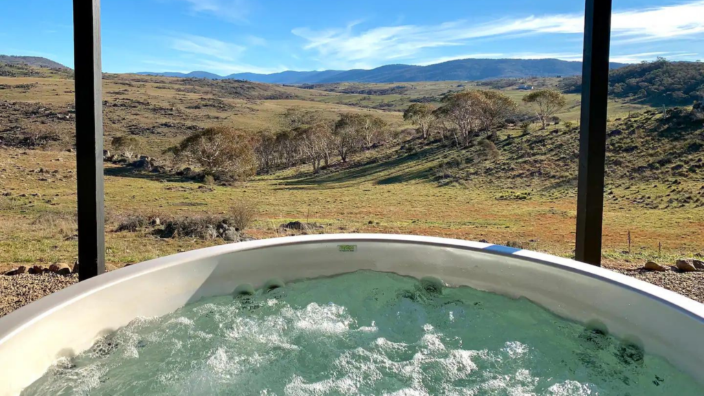 Outdoor spa overlooking fields and mountains at a top Jindabyne Airbnb