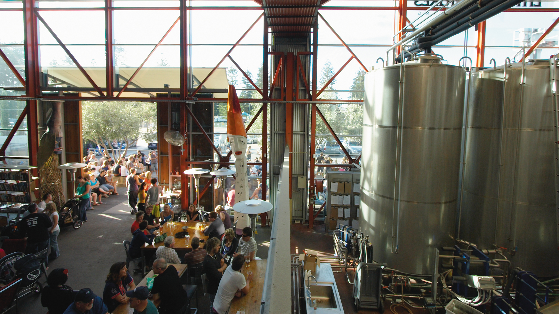 Little Creatures brewery with people sitting in large warehouse space with large beer brewing stainless steel fermenting barrels