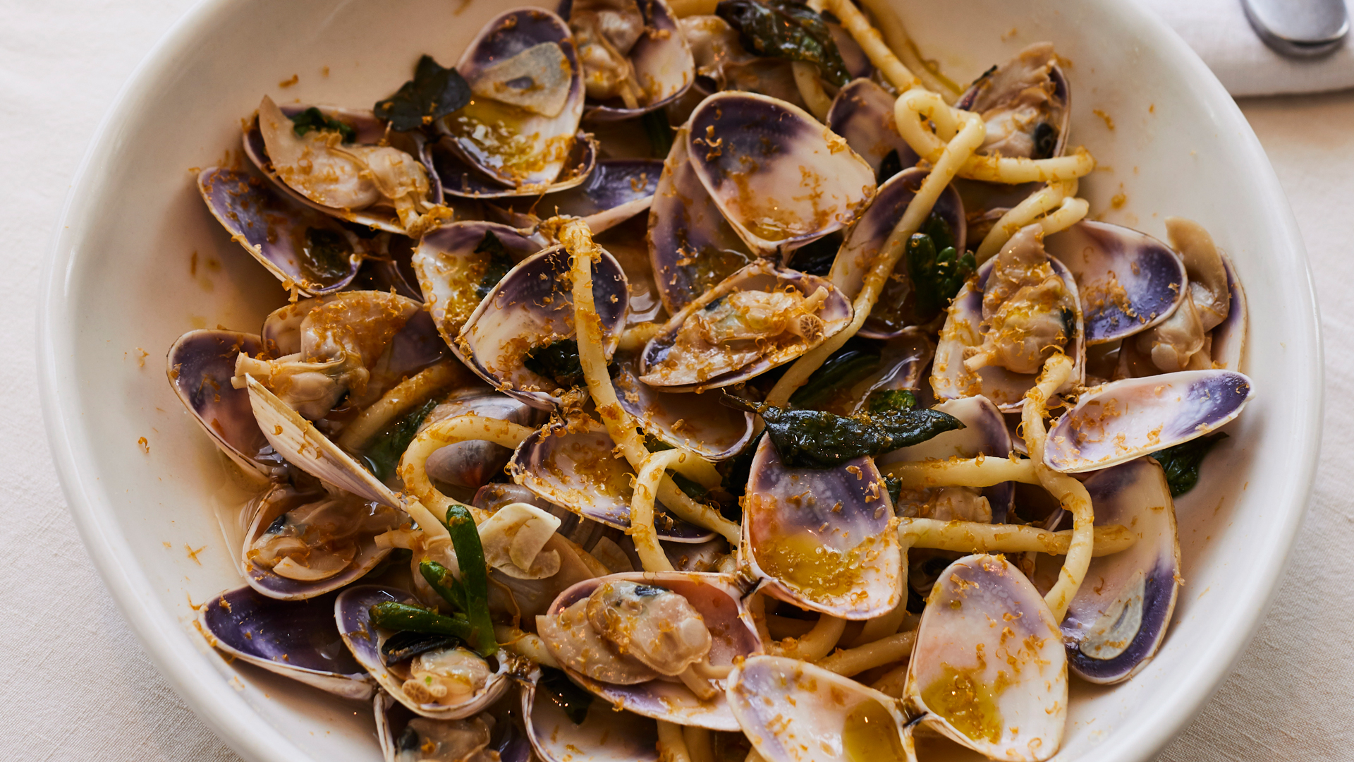 Pici pasta with opened cooked pipis in whote bowl