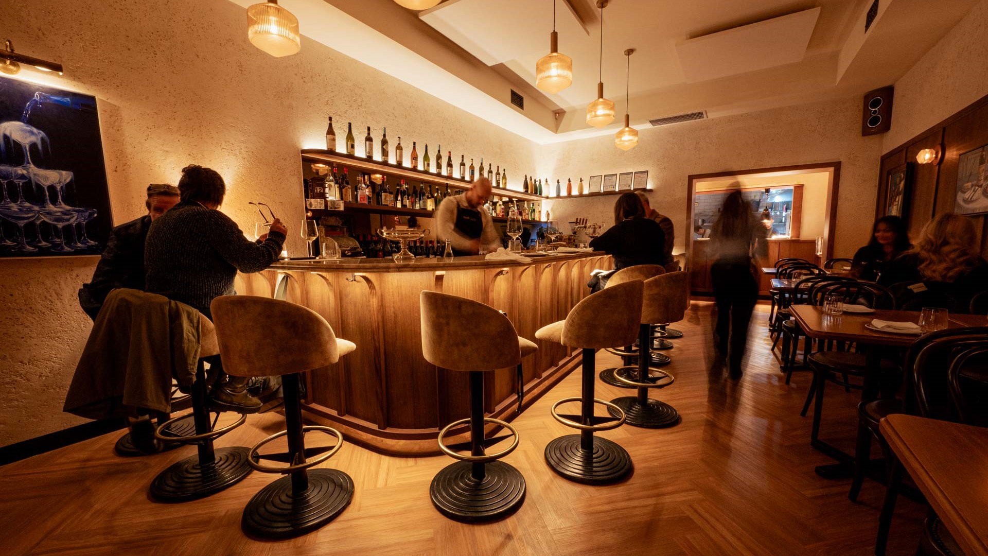 People sitting at the counter with warm lighting at Melbourne wine bar Bar Olo