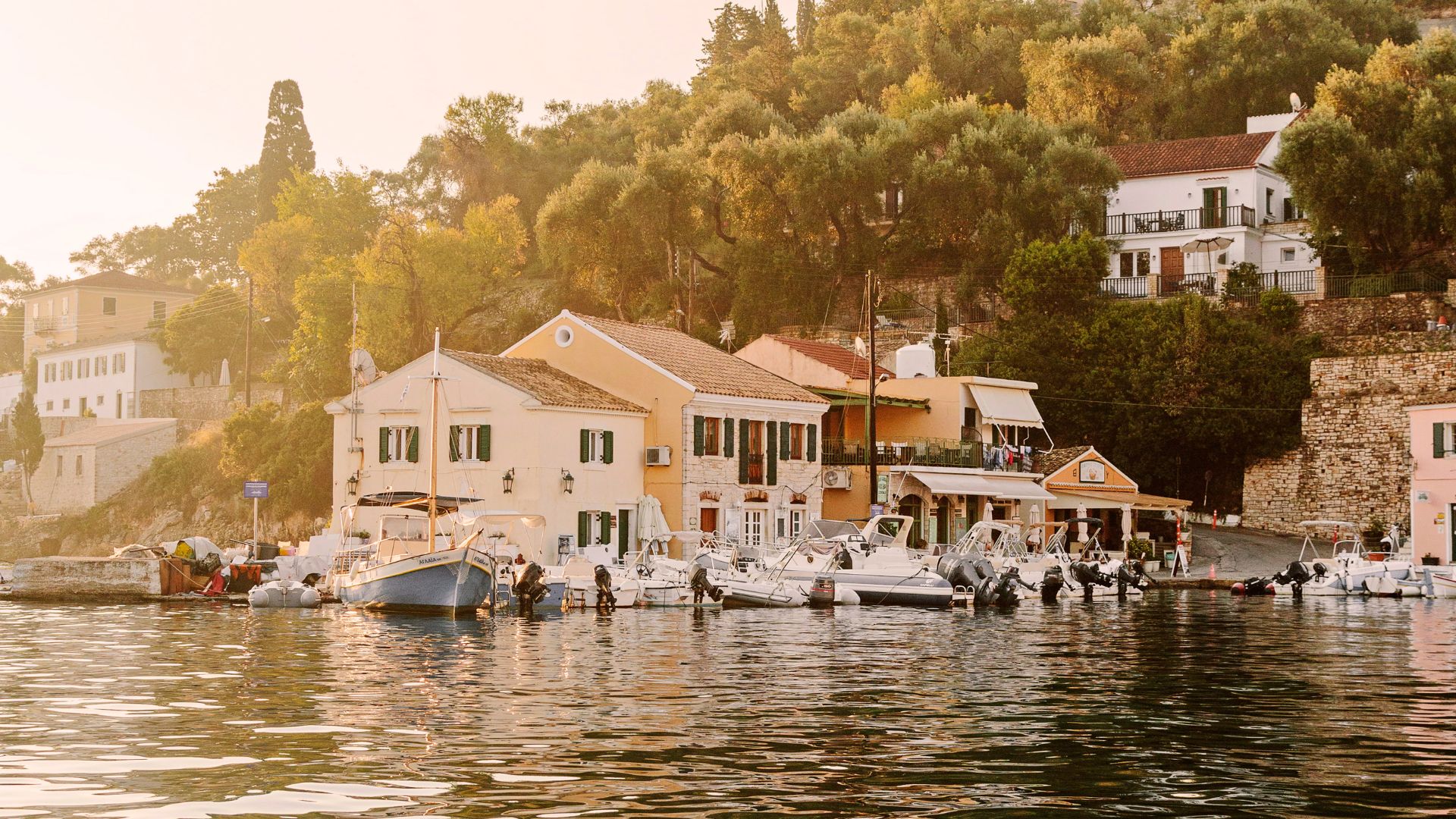 boats on water in front of houses in paxos island, greece