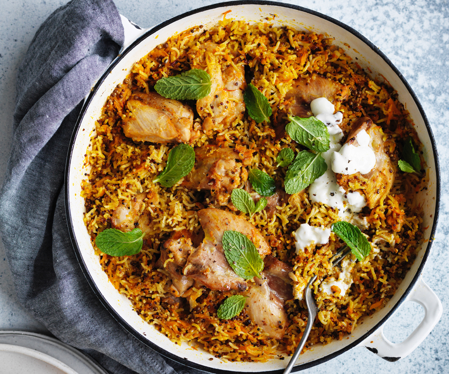 One-pot harissa chicken pilaf recipe in a round blue-rimmed enamel pot with draped grey tea towel on the side